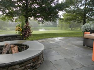 installed paver patio and fire pit overlooking a pond