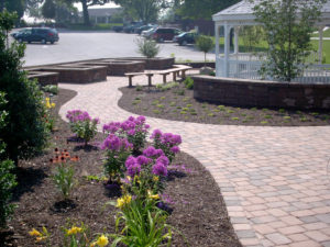 newly installed paver patio, mulch beds, and stone walls next to a parking lot