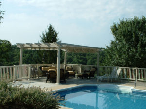 nicely fenced in pool area with shade structure and outdoor furniture