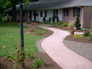 newly installed paver walkway, flower beds, stone beds, and shrubs in front of a red brick rancher