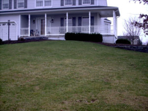 a grassy hill leading up to a white home