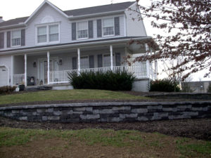 newly installed retaining walls and mulch beds in front of a white home