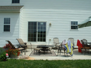 a concrete backyard porch area with lawn furniture
