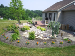 newly installed mulch bed with trees, shrubs flowers, stones and more
