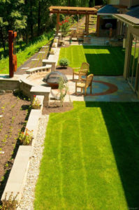 completed backyard landscape project with stone patio, fire pit, pergola, stone walls and more