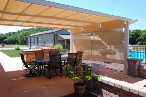 a covered pergola with patio furniture and retaining walls
