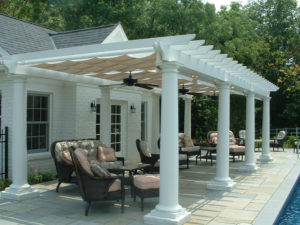covered pergola with patio furniture beneath, next to a pool