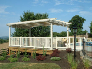 shaded pergola seating area with a mulch bed and fence