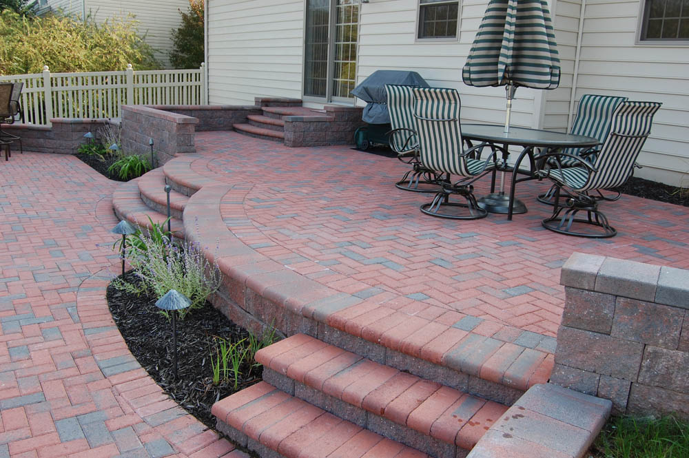 a red hardscaped patio with steps and retaining wall