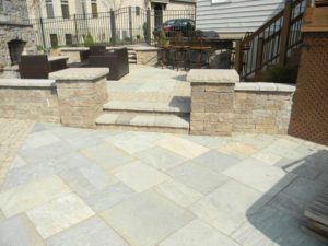 slate patio with retaining wall, pillars, patio furniture and fence