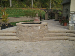 circular stone planting bed with a tree in the middle. steps and two stone hardscaped landing areas surround the build in bed