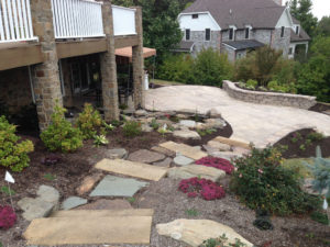 stone walkway leading down a mulch bed to a hardscaped paver patio