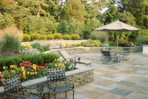 hardscaped patio with stone walls, miscellaneous flower beds and patio furniture
