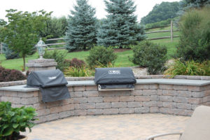 built in grills in a retaining wall on a backyard stone patio