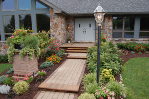 one of our creative walkway ideas. surrounded by flower beds, a stone pillar, and landscape lighting