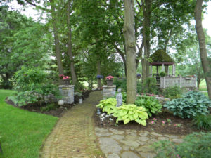 two different stone walkway ideas used in a wooded backyard landscape