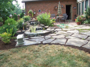 natural stone patio next to a water feature and leading up to a brick patio