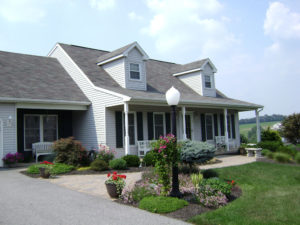 front of a white home with a porch, paver walkway, and well maintained paver walkway