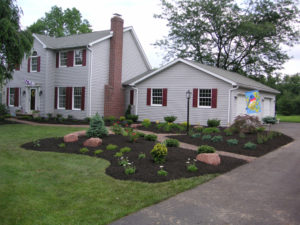 fresh black mulch beds surrounding a paver walkway leading from the driveway to front porch