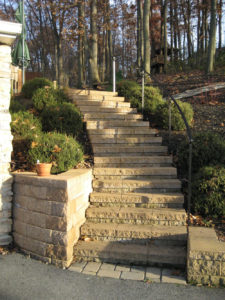stone staircase leading up a sloped flowerbed into a wooded area