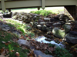 stone walls surround a small creek underneath a bridge