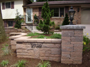 stone wall and pillar in front of a brick home