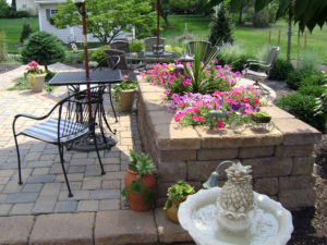 hardscaped paver patio with stone wall and enclosed flower bed