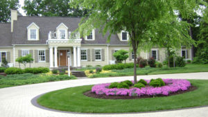 a circle driveway with a flowerbed and tree in front of a large Dover, PA area home