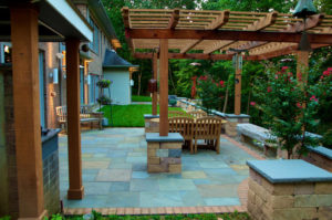 outdoor patio area with wooden pergola, stone pillar and stone walls