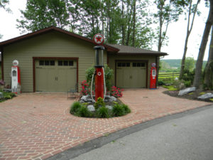 an old texaco gas pump. an asphalt drive connects to a brick drive and leads to a garage