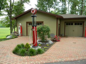 an old texaco gas pump in a mulch bed between two brick driveways