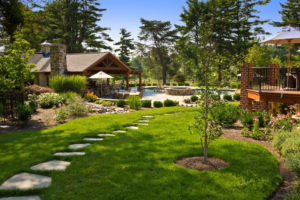 a beautiful backyard landscape. stone steppers lead back to a pool, patio, and firepit area