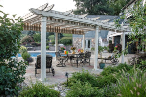 a patio seating area near a pool and under a pergola