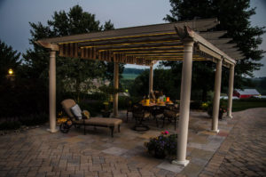 a lighted pergola with outdoor furniture dining area