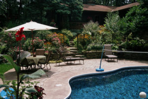 great sample of pool landscaping ideas. hardscaped patio, decorative stone walls, and bountiful flower beds