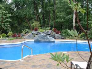 pool area with mulch bed and wooded area in the background