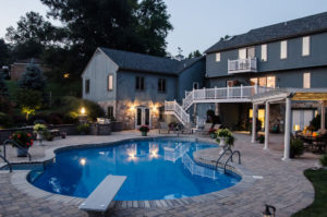 gorgeous backyard pool, hardscaped paver patio, pergola and seating area at dusk