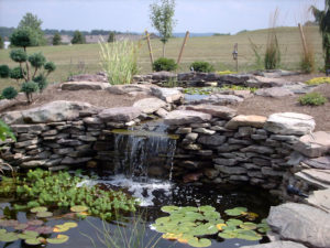 several water feature ideas used here - waterfall and two ponds complete with stone walls, lilypads and other water plants