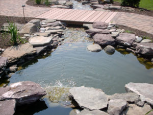 stone pond leading underneath a small bridge