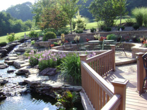 an amazing backyard seating area complete with circular paved patio, flower beds, waterfalls and ponds