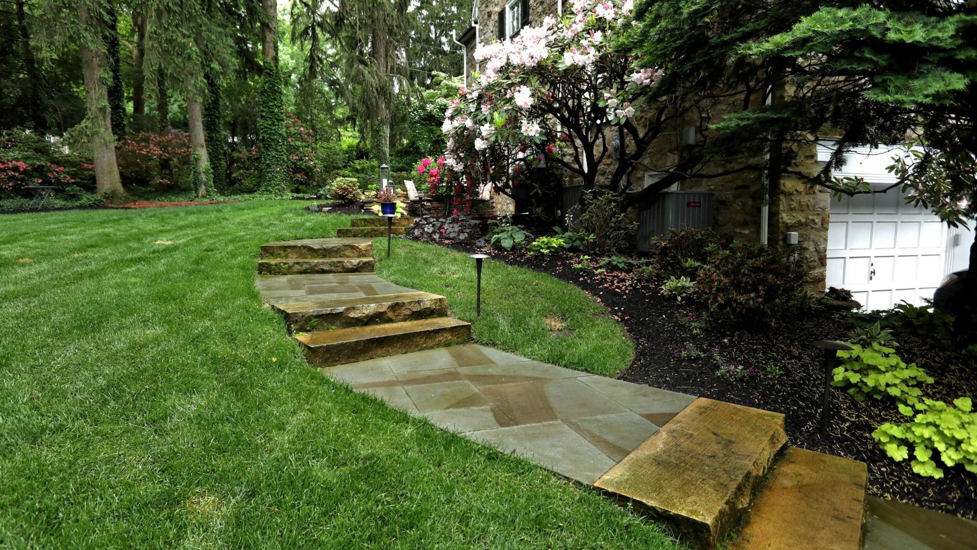hardscaped steps leading up in a backyard around a flower bed